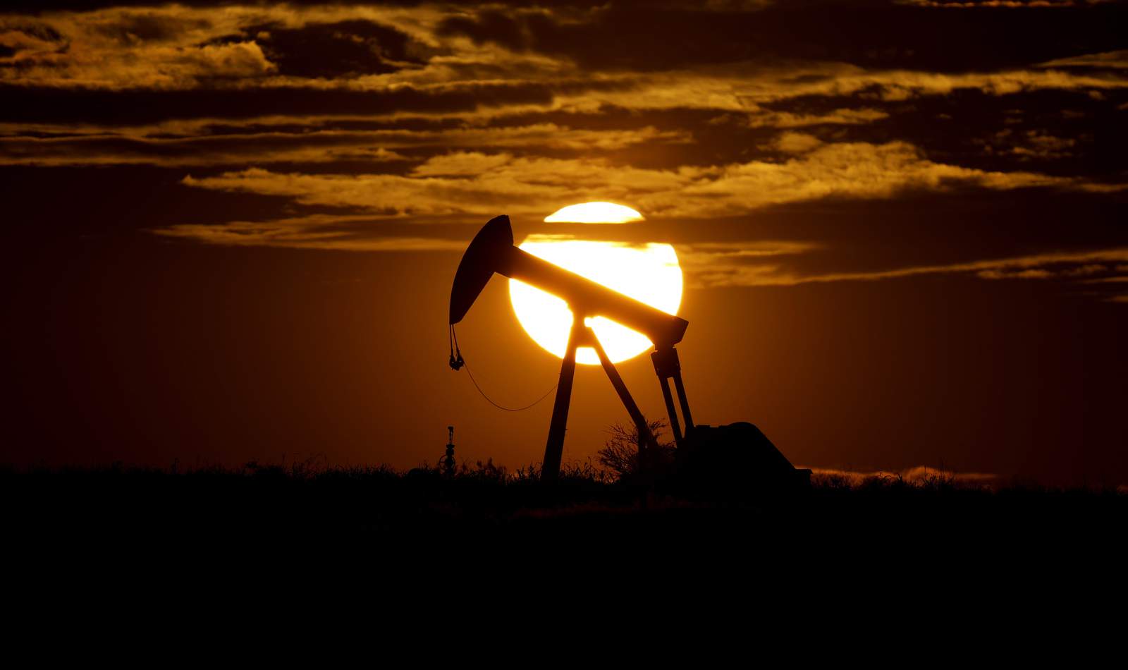 FILE - In this Wednesday, April 8, 2020, file photo, the sun sets behind an idle pump jack near Karnes City, Texas. Demand for oil continues to fall due to the new coronavirus outbreak. As demand for fuel plummeted worldwide and the oil industry faced a devastating drop in oil prices, the U.S. took the rare move of stepping into negotiations involving the member countries of OPEC and non-members such as Russia and Mexico. (AP Photo/Eric Gay, File)